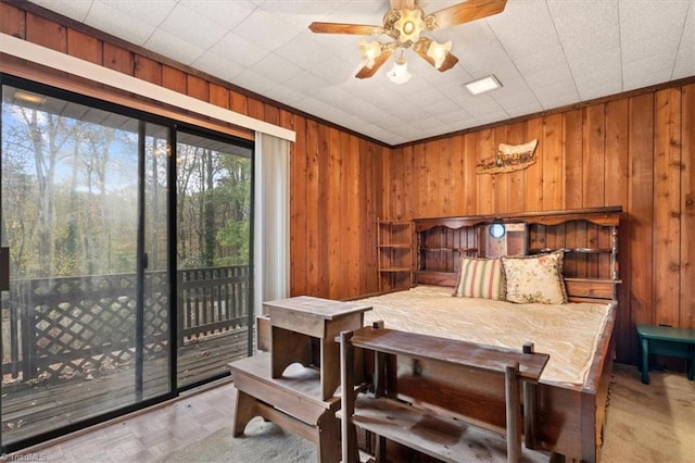 bedroom featuring wood walls, access to exterior, and ceiling fan