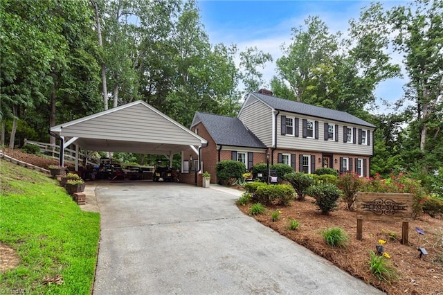 colonial home with brick siding, driveway, and a chimney