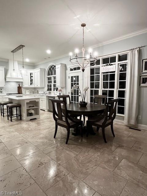 dining area with sink, a notable chandelier, and ornamental molding