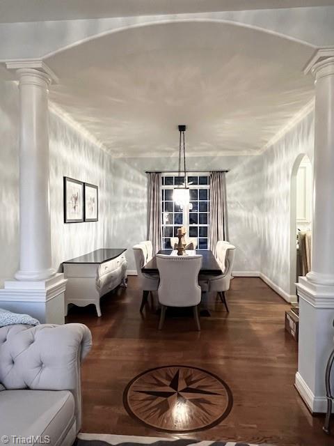 dining space with dark hardwood / wood-style floors and ornate columns