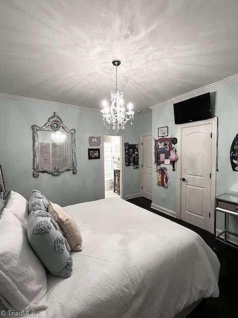 bedroom featuring ensuite bathroom, crown molding, and an inviting chandelier