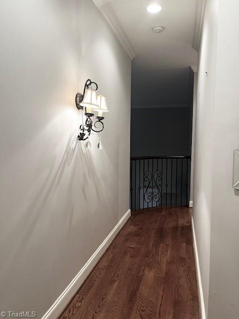 hallway with dark hardwood / wood-style floors and ornamental molding