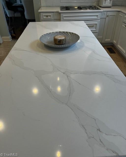 interior details featuring light stone countertops and gas stovetop