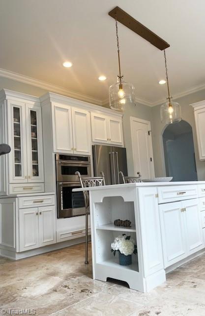 kitchen featuring white cabinets, hanging light fixtures, appliances with stainless steel finishes, and crown molding