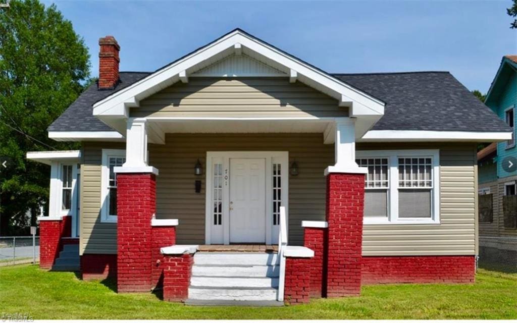 bungalow featuring covered porch and a front yard