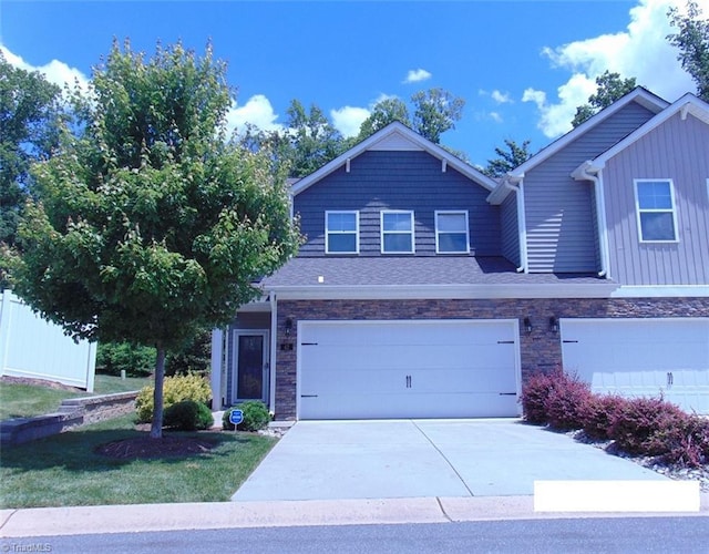 view of front facade featuring stone siding, a front lawn, concrete driveway, and a garage