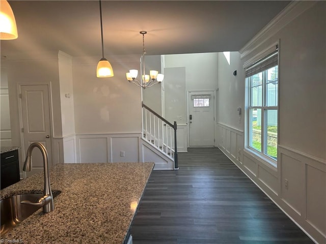 foyer with dark wood finished floors, an inviting chandelier, stairs, wainscoting, and a decorative wall