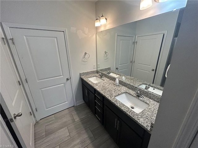 full bathroom with a sink, baseboards, and double vanity