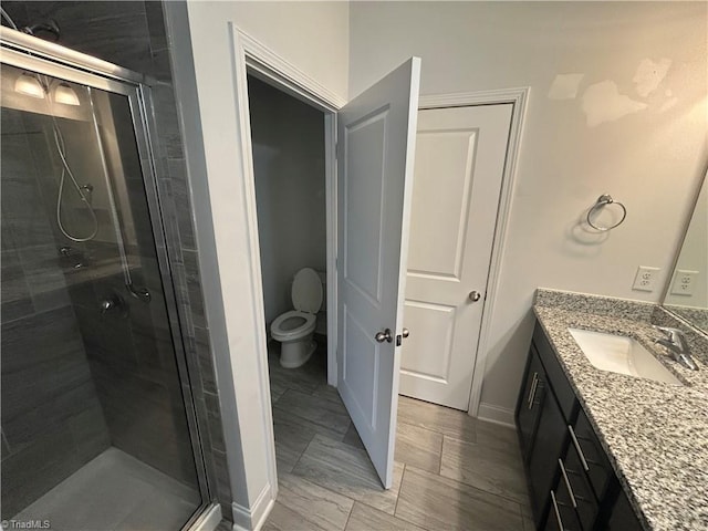 bathroom with vanity, a shower stall, and toilet