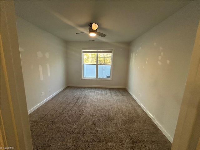 carpeted spare room featuring baseboards and ceiling fan