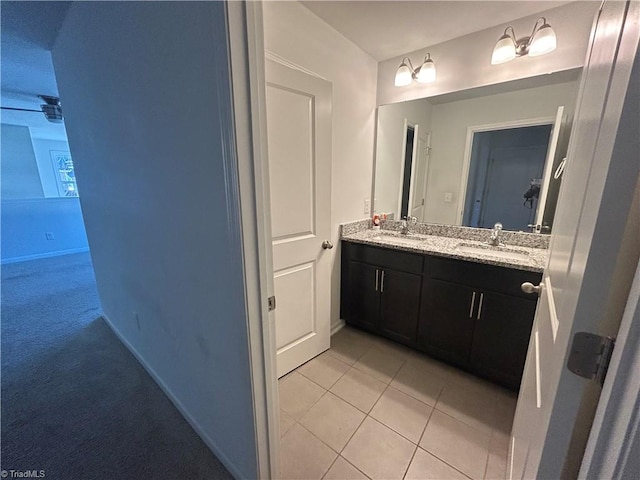 bathroom featuring a sink, baseboards, double vanity, and tile patterned floors