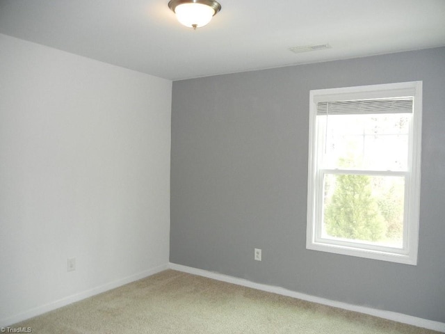 unfurnished room with visible vents, a healthy amount of sunlight, light colored carpet, and baseboards