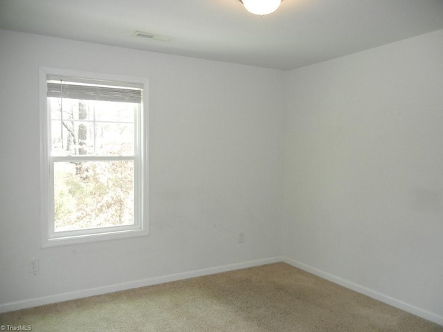 unfurnished room with visible vents, light colored carpet, and baseboards