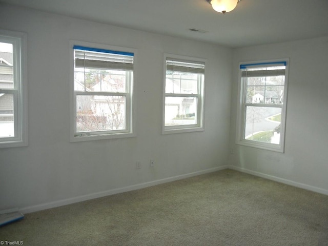 carpeted spare room with visible vents and baseboards