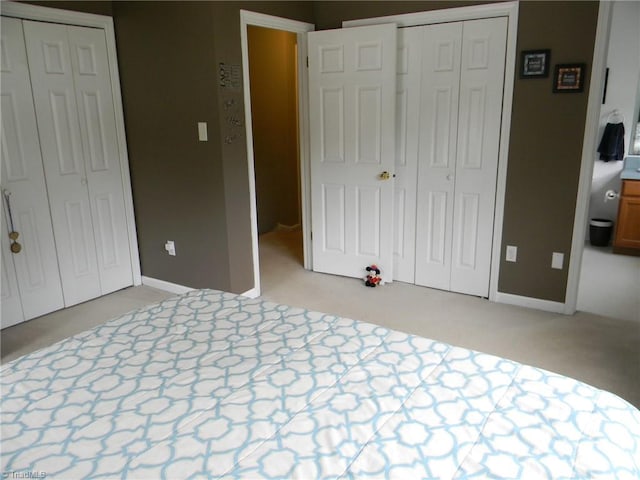 unfurnished bedroom with multiple closets and light colored carpet