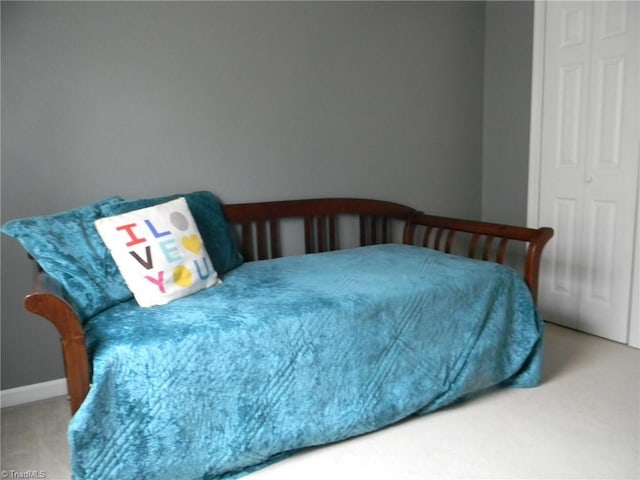 carpeted bedroom featuring baseboards and a closet