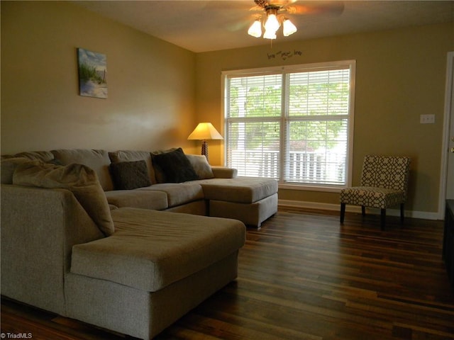 living area featuring baseboards, ceiling fan, and dark wood-style floors