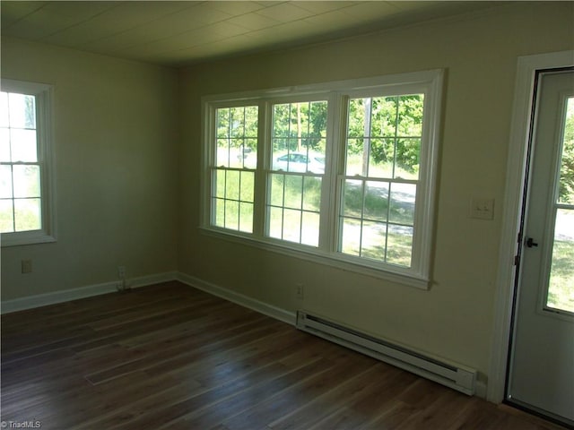 unfurnished room featuring baseboard heating, dark hardwood / wood-style flooring, and plenty of natural light