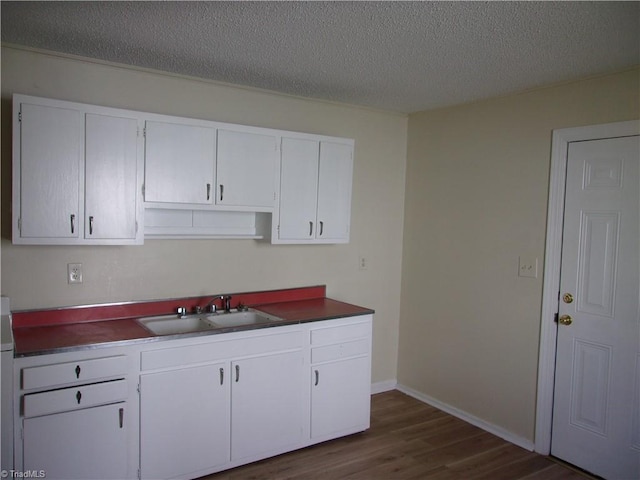 kitchen with white cabinets, dark hardwood / wood-style floors, sink, and a textured ceiling