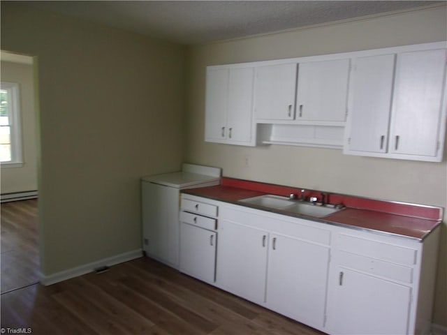 kitchen with dark hardwood / wood-style floors, sink, a baseboard heating unit, and white cabinetry