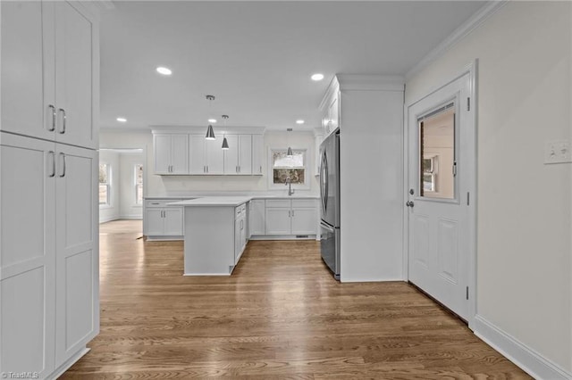 kitchen featuring a wealth of natural light, white cabinets, freestanding refrigerator, and ornamental molding