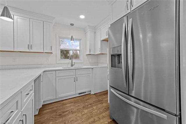 kitchen featuring light countertops, stainless steel fridge with ice dispenser, a sink, and white cabinets