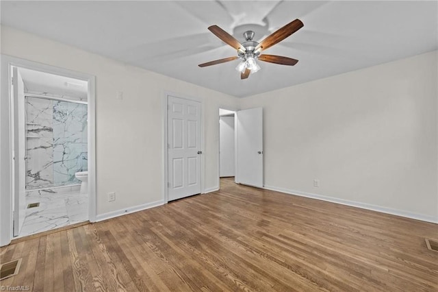 unfurnished bedroom with ensuite bath, visible vents, baseboards, and wood finished floors