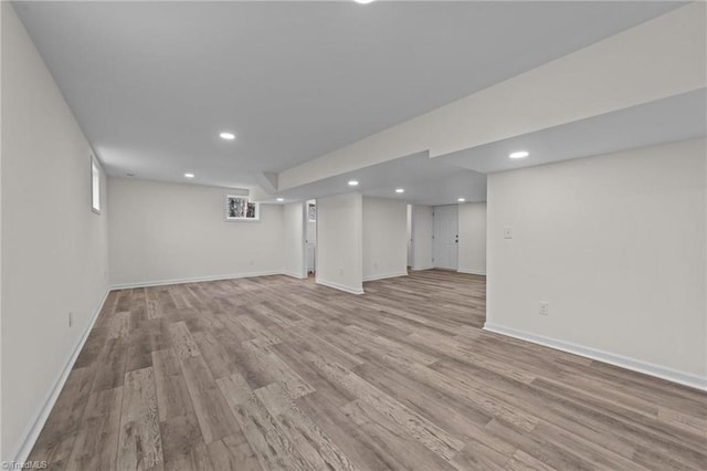 basement featuring light wood-style floors, baseboards, and recessed lighting