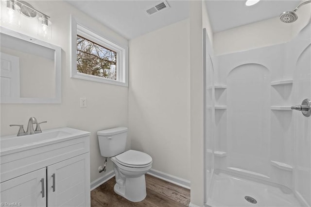bathroom featuring visible vents, walk in shower, toilet, vanity, and wood finished floors