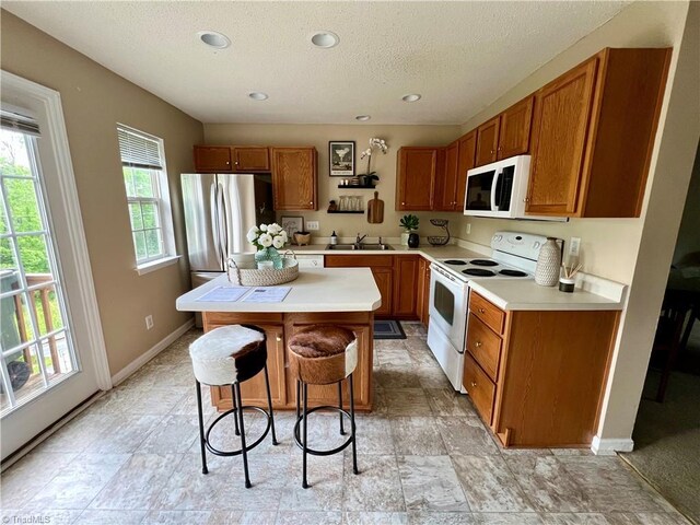 88 Tannenbaum Cir, Greensboro, NC 27410 - kitchen featuring white appliances, a sink, brown cabinetry, a textured ceiling, and light countertops
