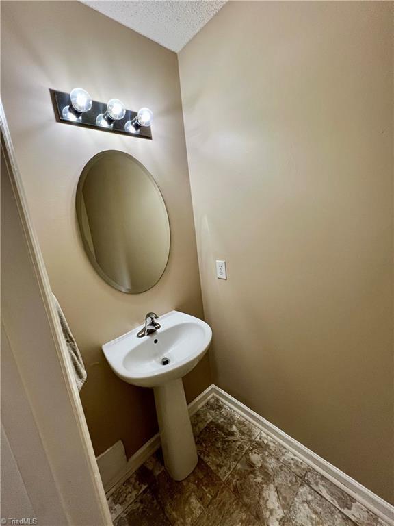 88 Tannenbaum Cir, Greensboro, NC 27410 - bathroom featuring baseboards, a textured ceiling, and a sink