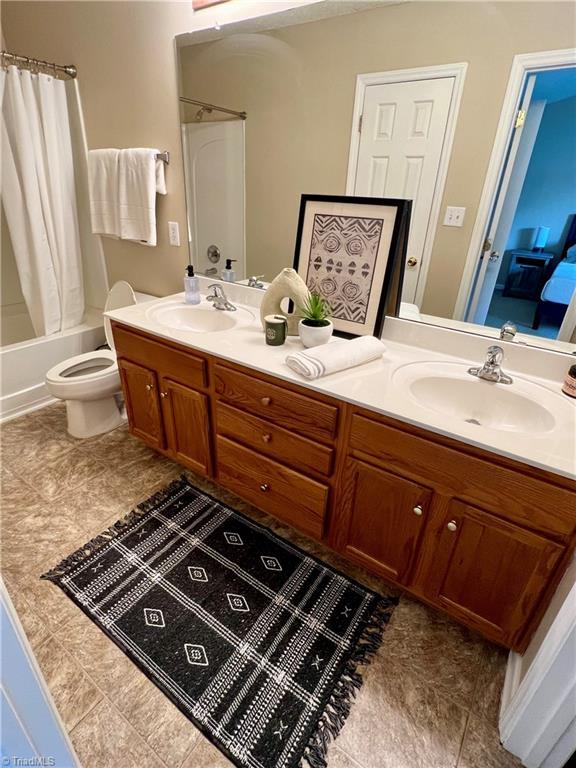 88 Tannenbaum Cir, Greensboro, NC 27410 - full bath with double vanity, shower / bath combo with shower curtain, toilet, and tile patterned flooring