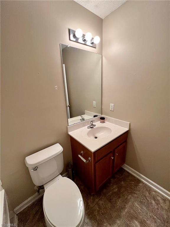 88 Tannenbaum Cir, Greensboro, NC 27410 - bathroom with vanity, a textured ceiling, toilet, and baseboards