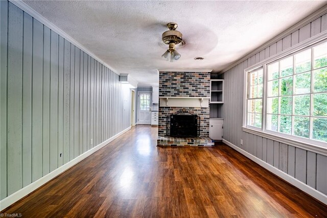 3230 Kinnamon Rd, Winston-Salem, NC 27104 - unfurnished living room featuring a textured ceiling, a wealth of natural light, ornamental molding, and dark wood-style floors
