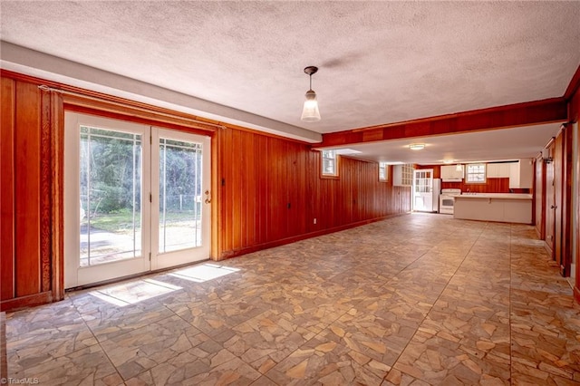 3230 Kinnamon Rd, Winston-Salem, NC 27104 - spare room featuring wood walls, a wealth of natural light, a textured ceiling, and stone finish flooring