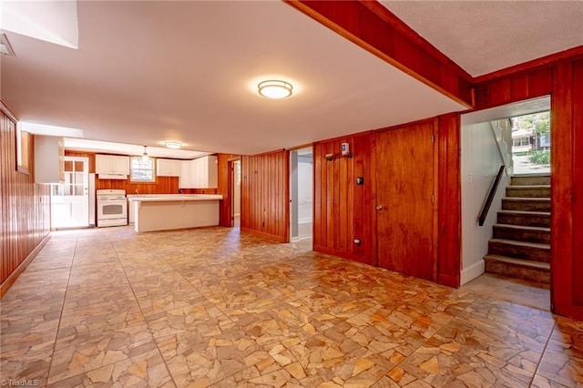 3230 Kinnamon Rd, Winston-Salem, NC 27104 - unfurnished living room featuring wooden walls, stone finish flooring, a healthy amount of sunlight, and stairs