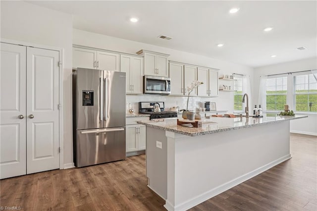 162 Bryson Blvd, Lexington, NC 27295 - kitchen featuring appliances with stainless steel finishes, dark wood-style floors, an island with sink, tasteful backsplash, and light stone counters