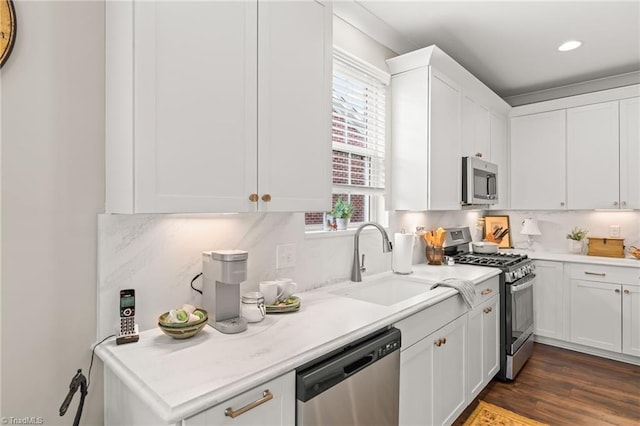 kitchen with a sink, light countertops, appliances with stainless steel finishes, white cabinetry, and tasteful backsplash