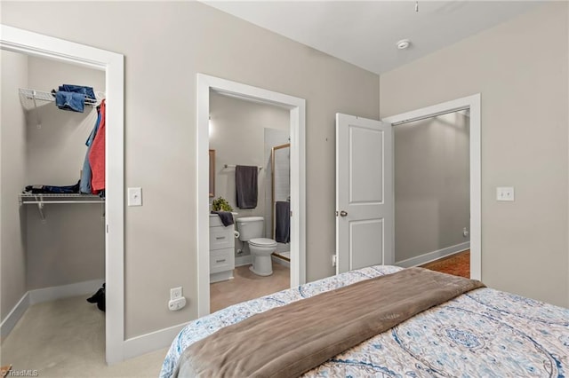 bedroom with a closet, baseboards, ensuite bath, and a spacious closet