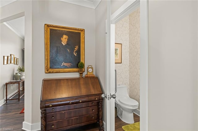 bathroom with baseboards, toilet, wood finished floors, and crown molding