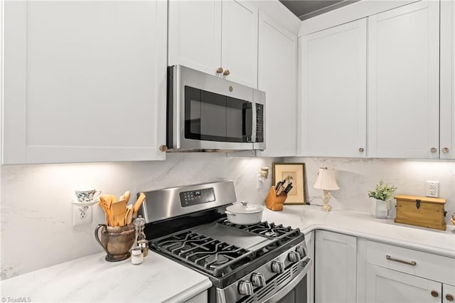 kitchen featuring tasteful backsplash, appliances with stainless steel finishes, white cabinets, and light countertops