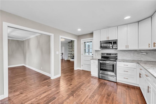 kitchen with tasteful backsplash, white cabinets, stainless steel appliances, and wood finished floors