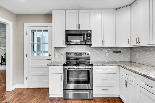 kitchen with white cabinetry, dark wood-type flooring, backsplash, and stainless steel appliances