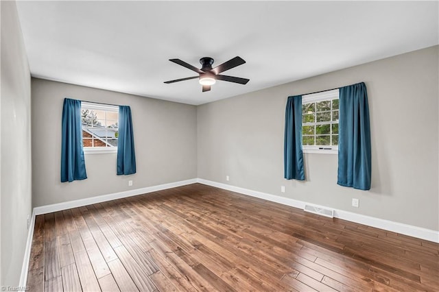 unfurnished room featuring a wealth of natural light, visible vents, and hardwood / wood-style flooring