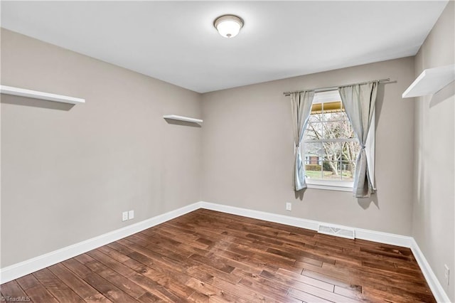 empty room featuring visible vents, baseboards, and hardwood / wood-style floors