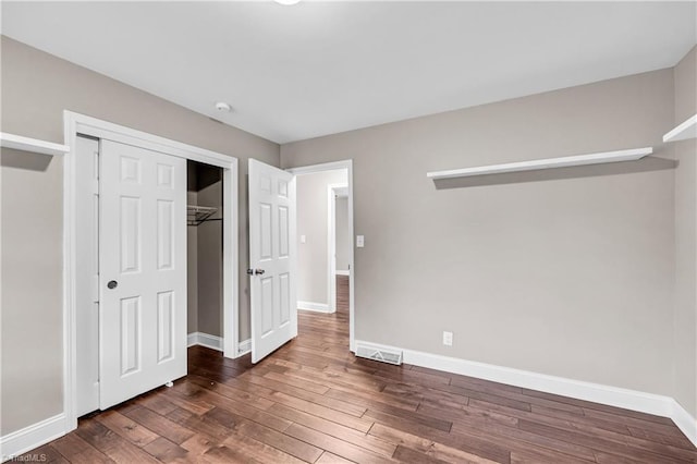 unfurnished bedroom with a closet, baseboards, visible vents, and wood finished floors