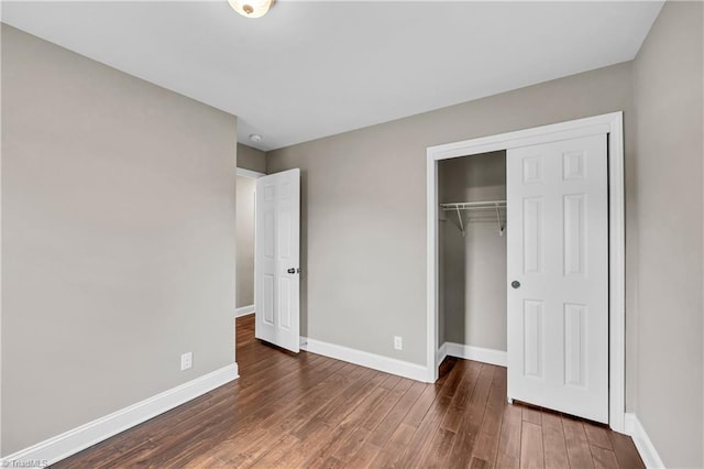 unfurnished bedroom featuring a closet, baseboards, and wood finished floors