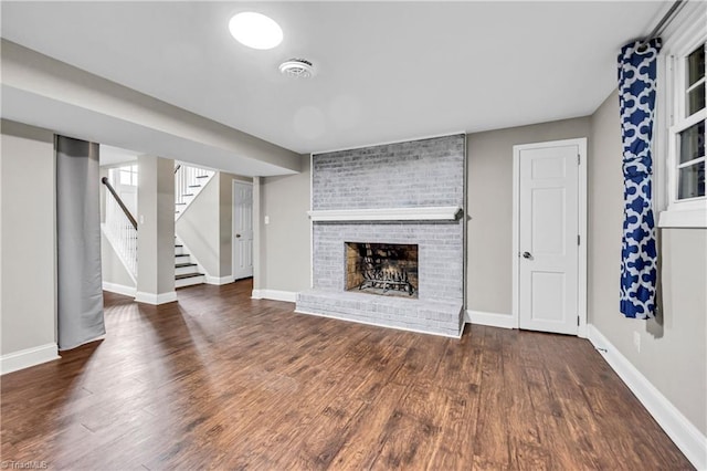 unfurnished living room with baseboards, a fireplace, wood finished floors, and stairs