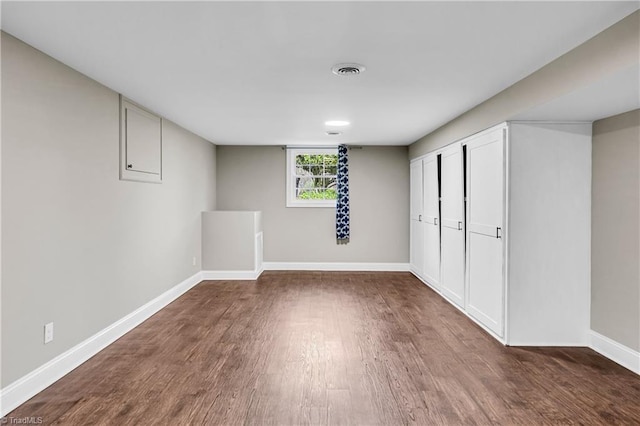 basement with wood finished floors, visible vents, and baseboards