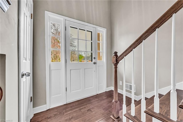 foyer entrance featuring visible vents, baseboards, dark wood-type flooring, and stairs